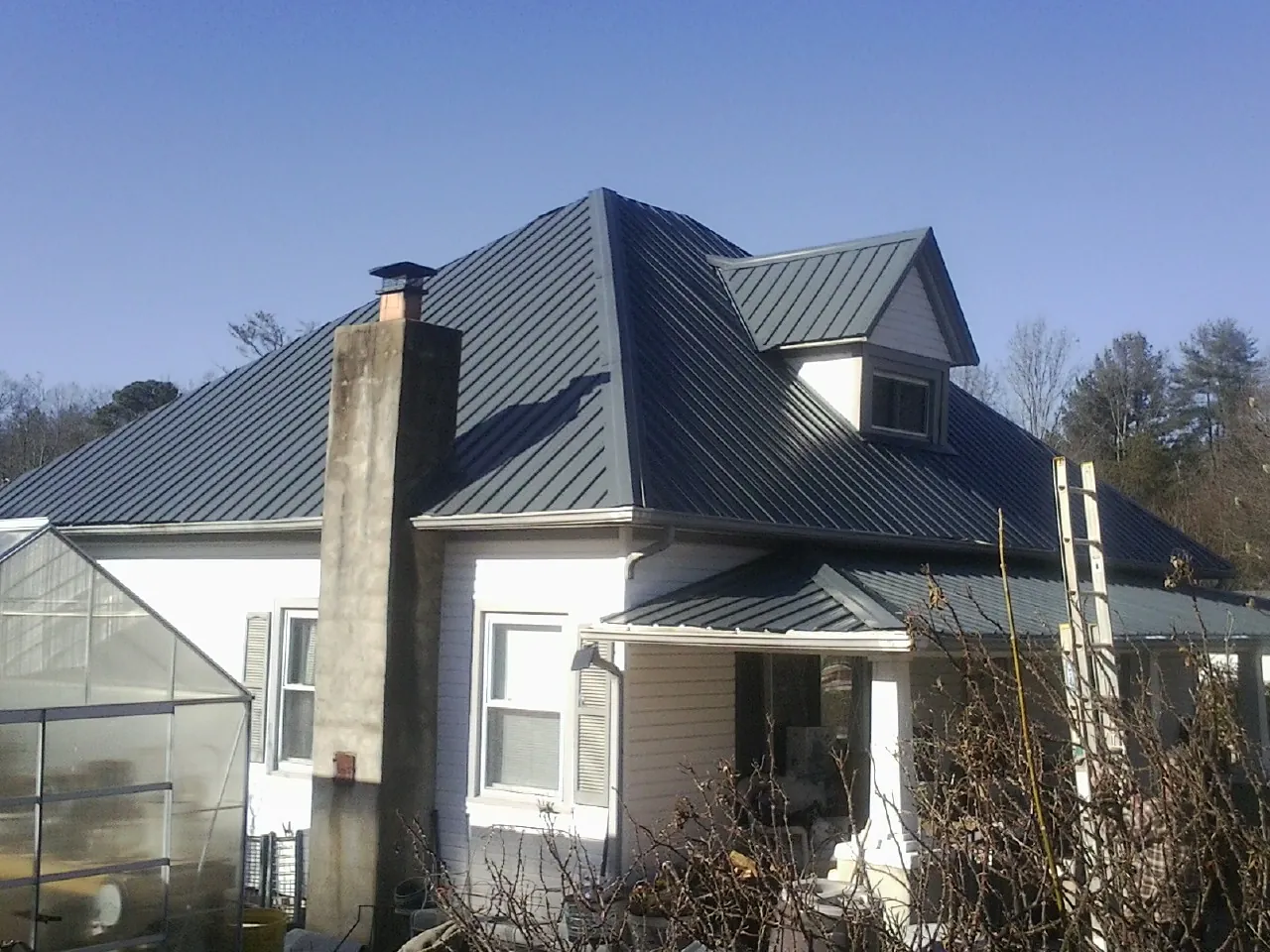 Dark blue standing seam metal roof on a white farmhouse with dormer — Slate & Tile Roof Repair by Roofing Brothers in Roseboro