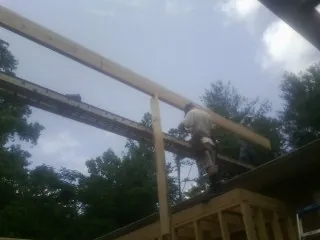 Carpenter setting a ridge beam over a new addition frame — Ice Dam Removal by Roofing Brothers in Roseboro