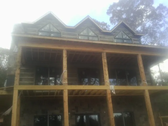 Dormers and porch framing on a large log home under construction — Roof Coating work by our crew in Roseboro