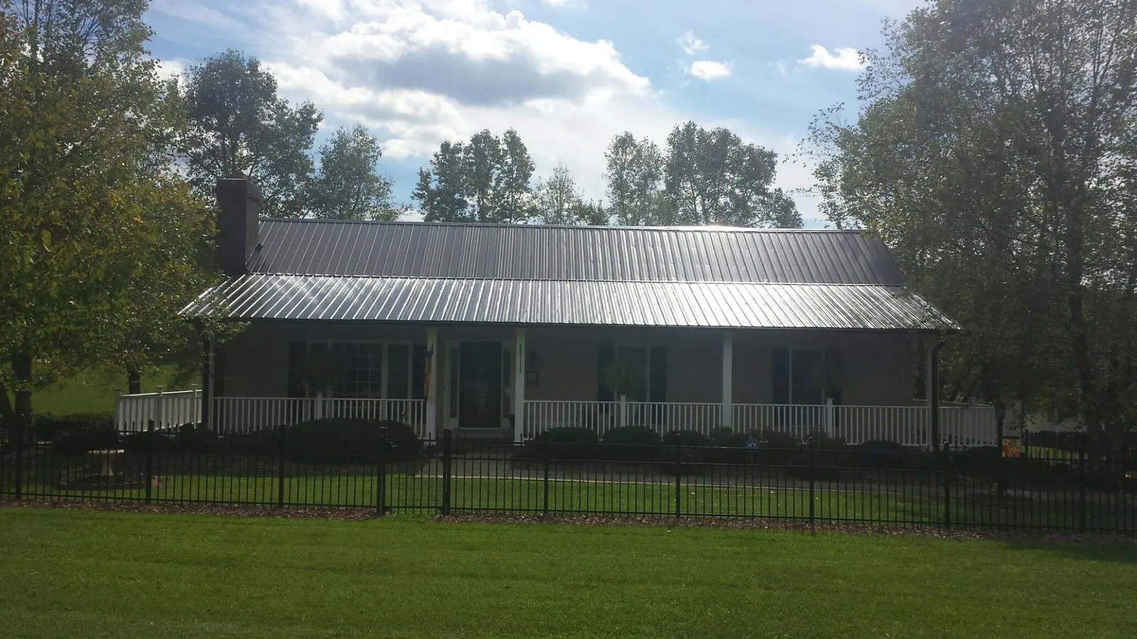 Gray metal roof on a brick ranch with a full width front porch — Gutter Guard Installation work by our crew in Roseboro