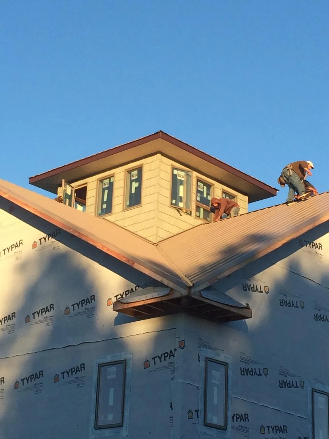 Roofers working around a rooftop cupola on a new metal roof at sunset — Roof Waterproofing in Roseboro by Roofing Brothers